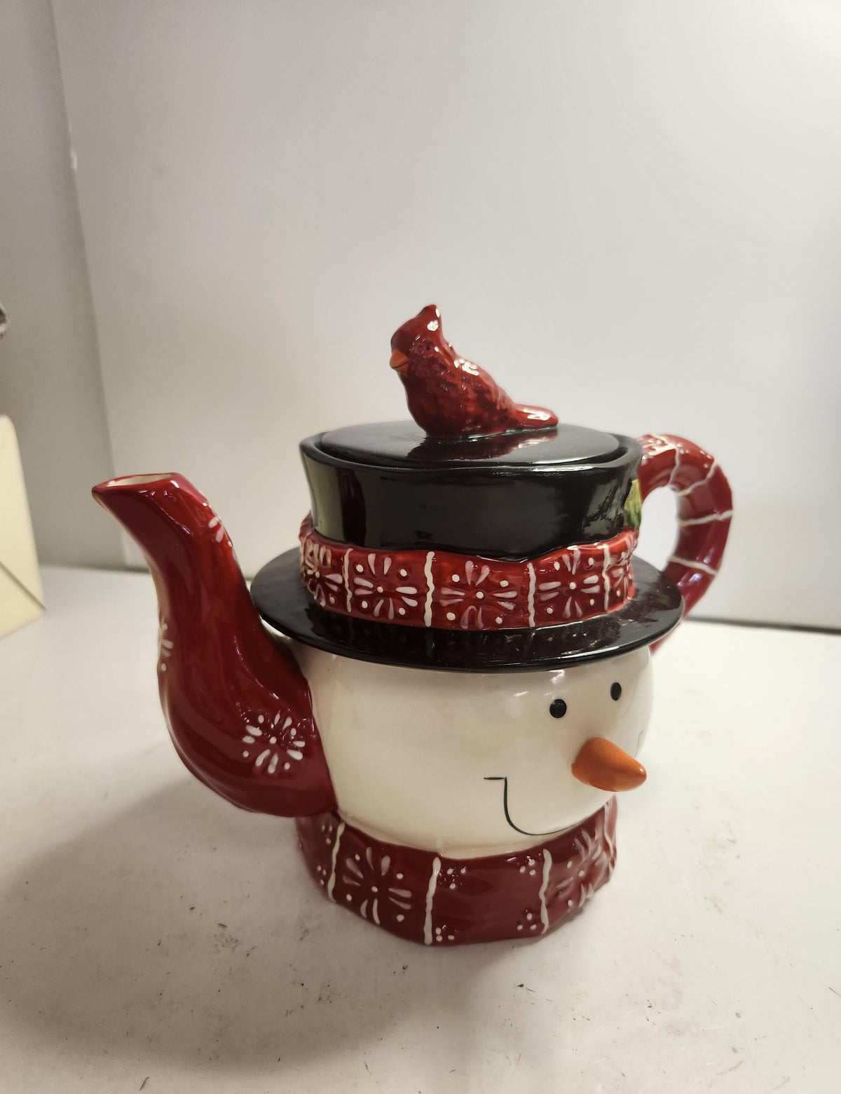 Ceramic snowman teapot with red plaid scarf and hat and red cardinal on the lid, view 4