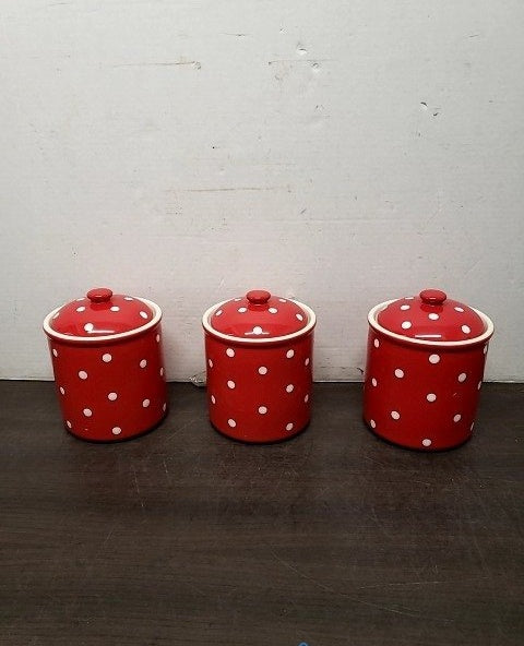 Three graduated red ceramic canisters with white polka dots and lids, view 2