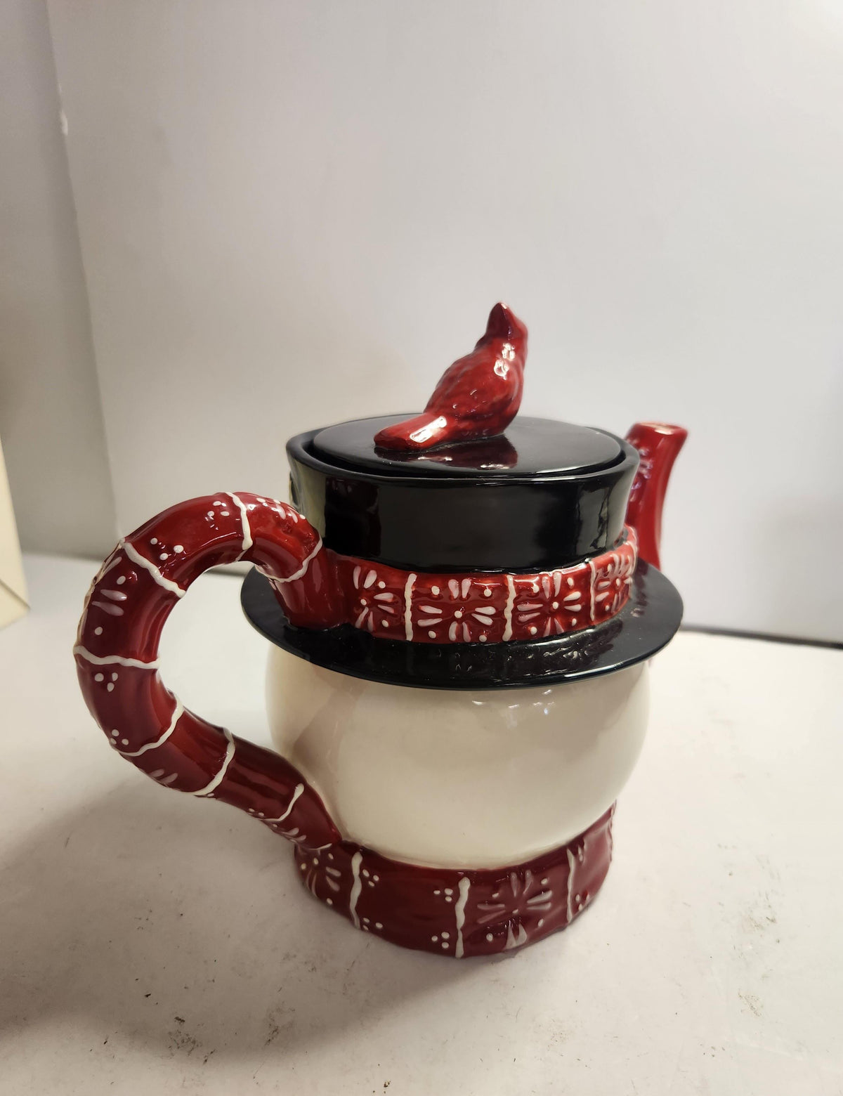 Ceramic snowman teapot with red plaid scarf and hat and red cardinal on the lid, view 3