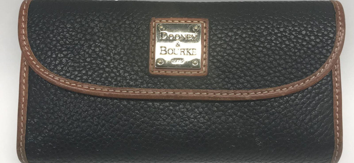 Dooney and Bourke black pebble grain leather clutch wallet with brown trim and front plaque, view 3
