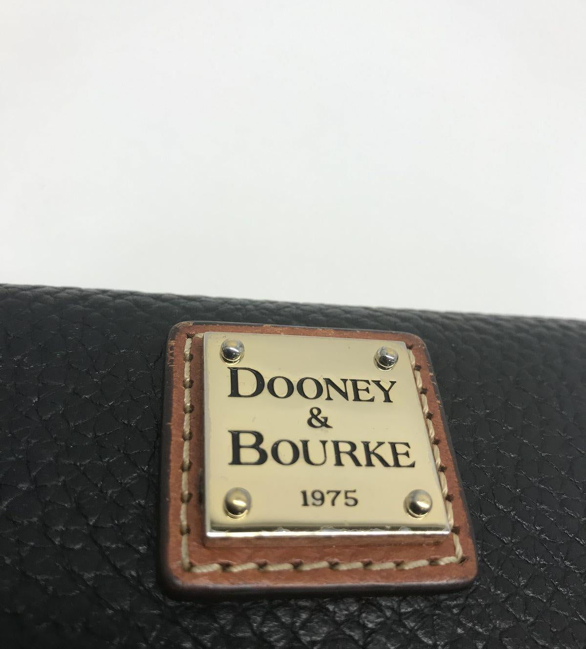 Dooney and Bourke black pebble grain leather clutch wallet with brown trim and front plaque, view 7