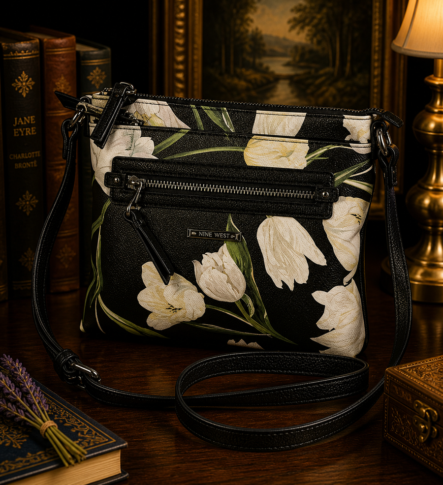 Black crossbody bag with large white floral pattern and front zip pocket