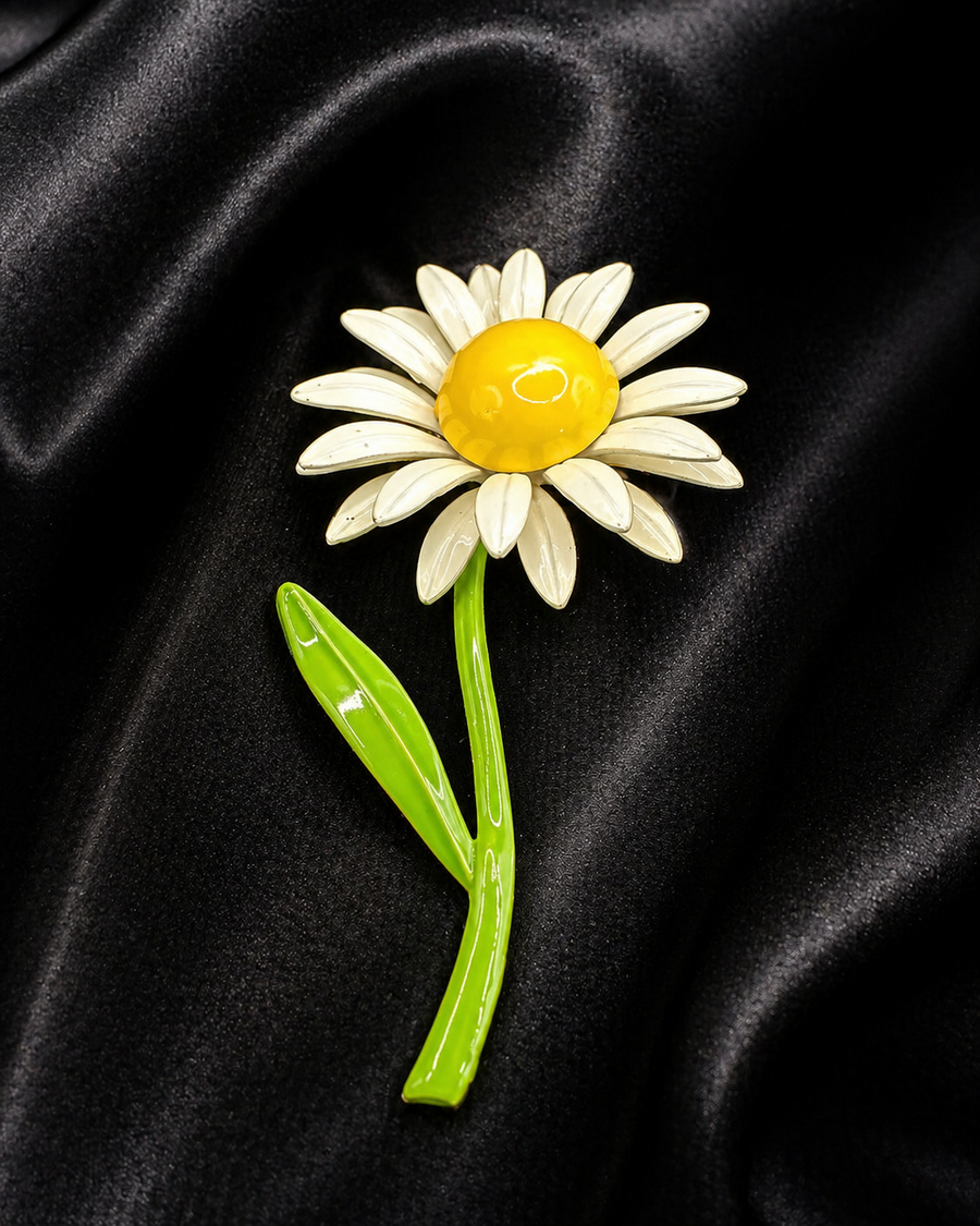 White daisy brooch with yellow center and long green stem with single leaf