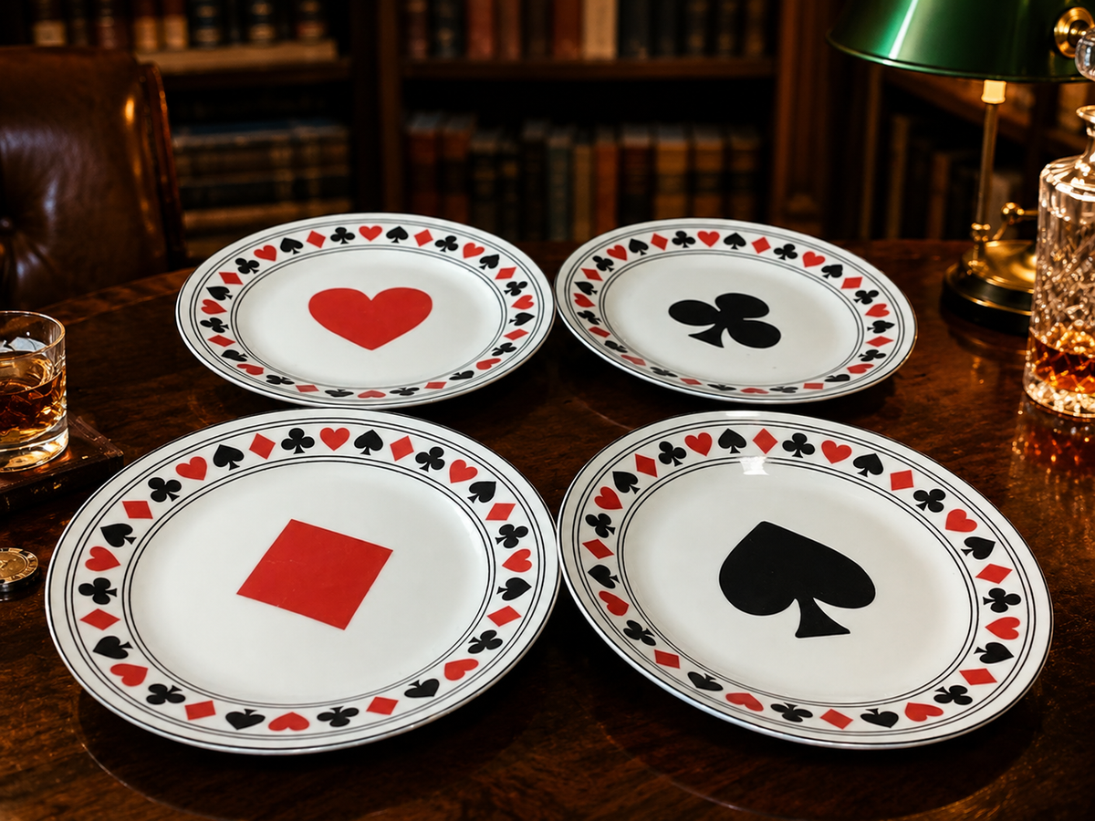 Four white dessert plates with black and red playing card suit centers