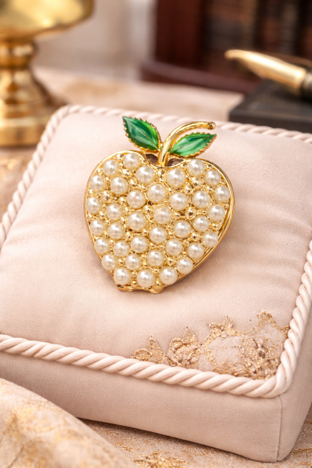 Gold-tone apple brooch covered in ivory faux pearls with green enamel leaves