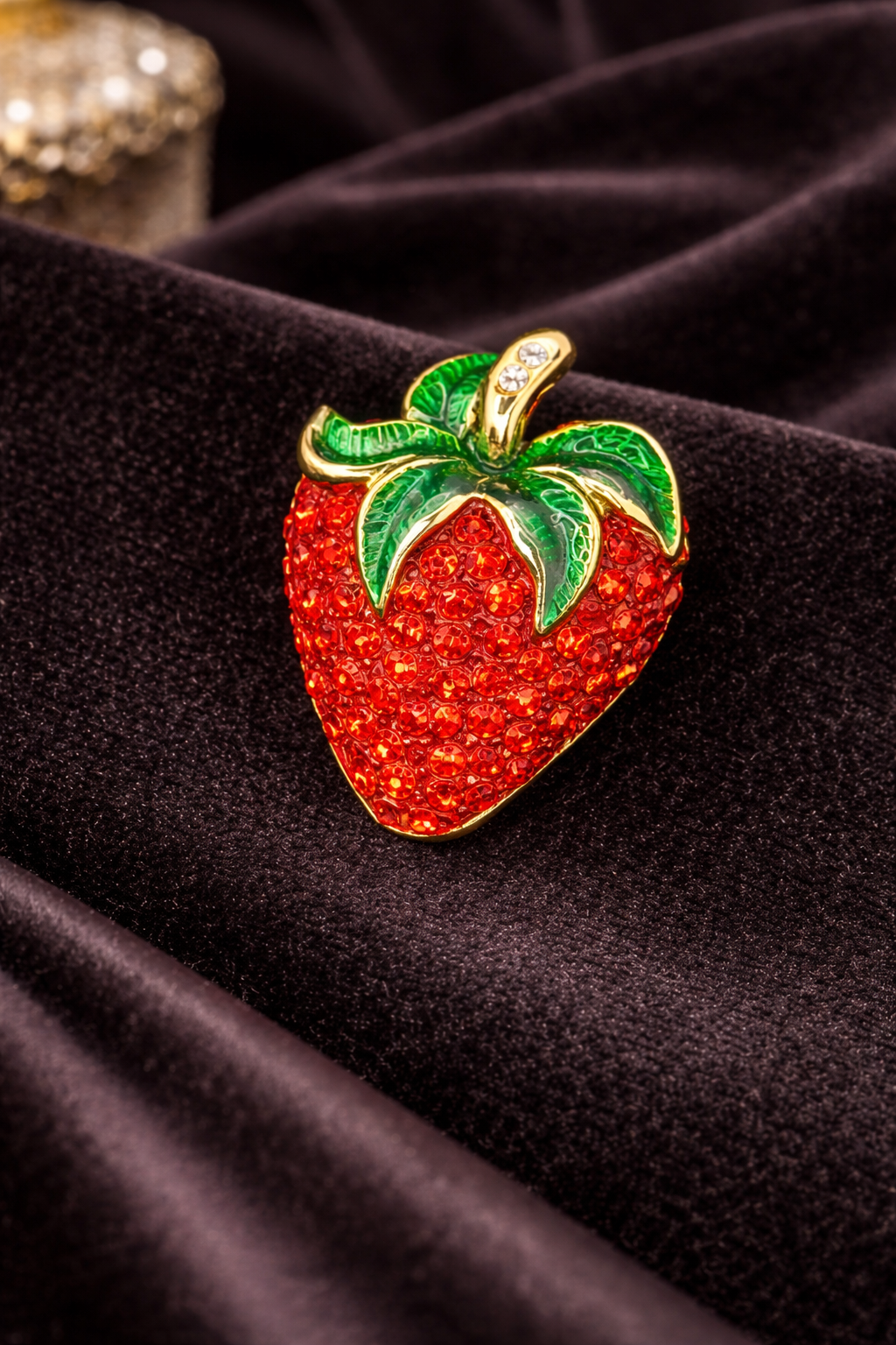 Gold-tone strawberry brooch with red pavé rhinestones and sweeping green enamel leaves