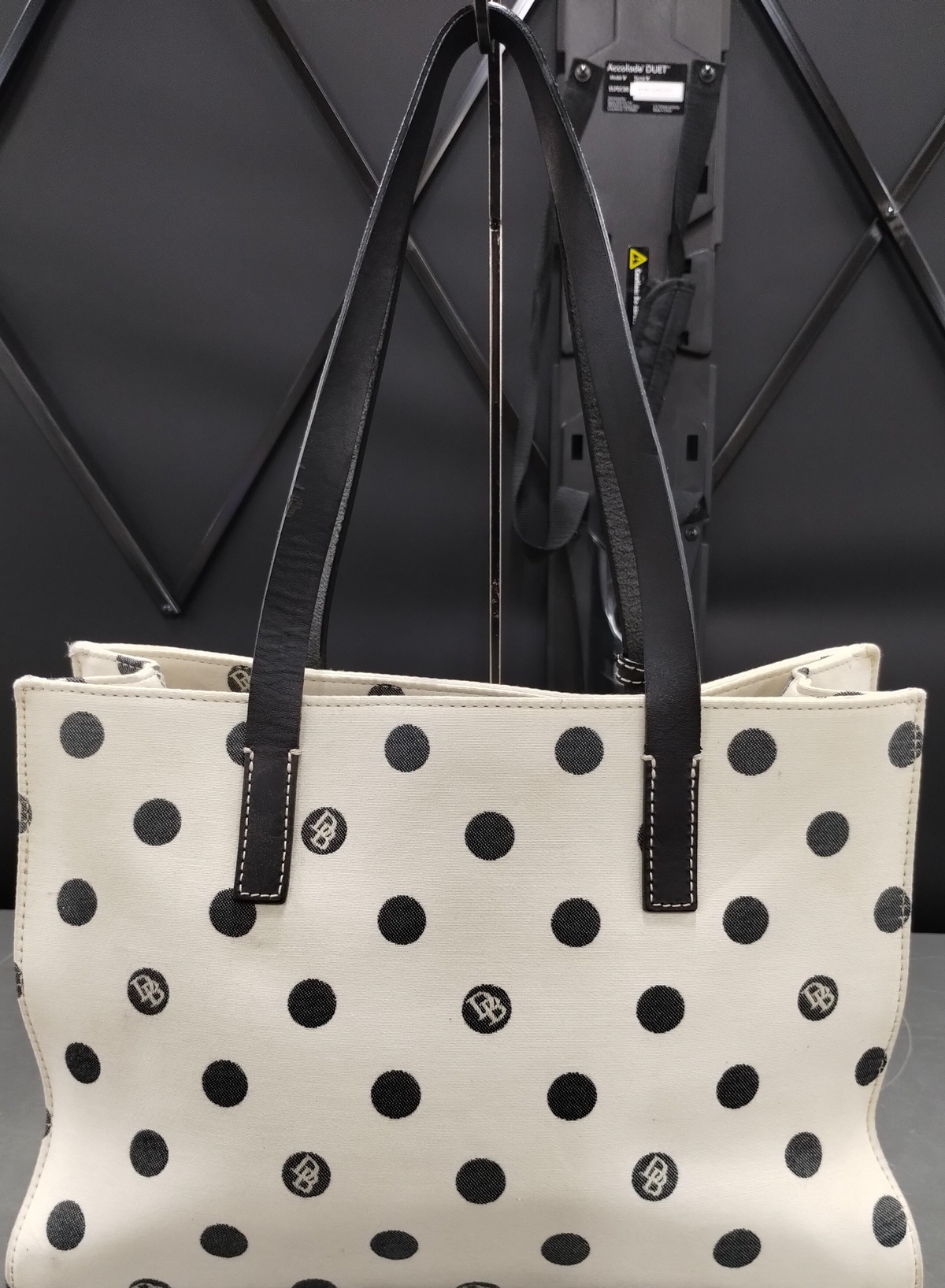 Dooney and Bourke cream canvas tote with black polka dots, black leather straps and blue duck charm, view 4