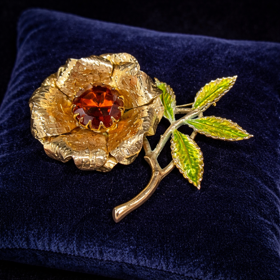 Signed Sarah Coventry gold-tone flower brooch with amber rhinestone center and green enamel leaves