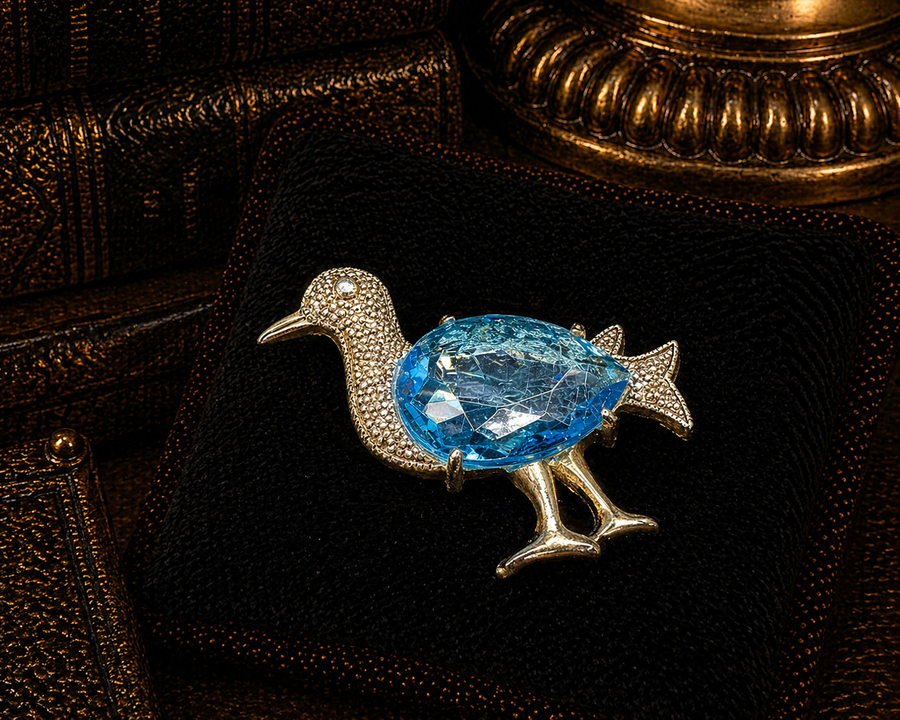 Silver-tone duck brooch with large faceted light blue crystal body