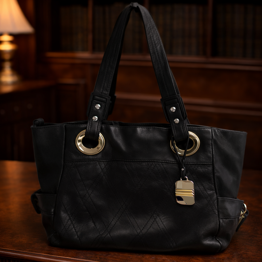 Navy blue leather slouchy tote with grommet shoulder straps and gold-tone logo charm