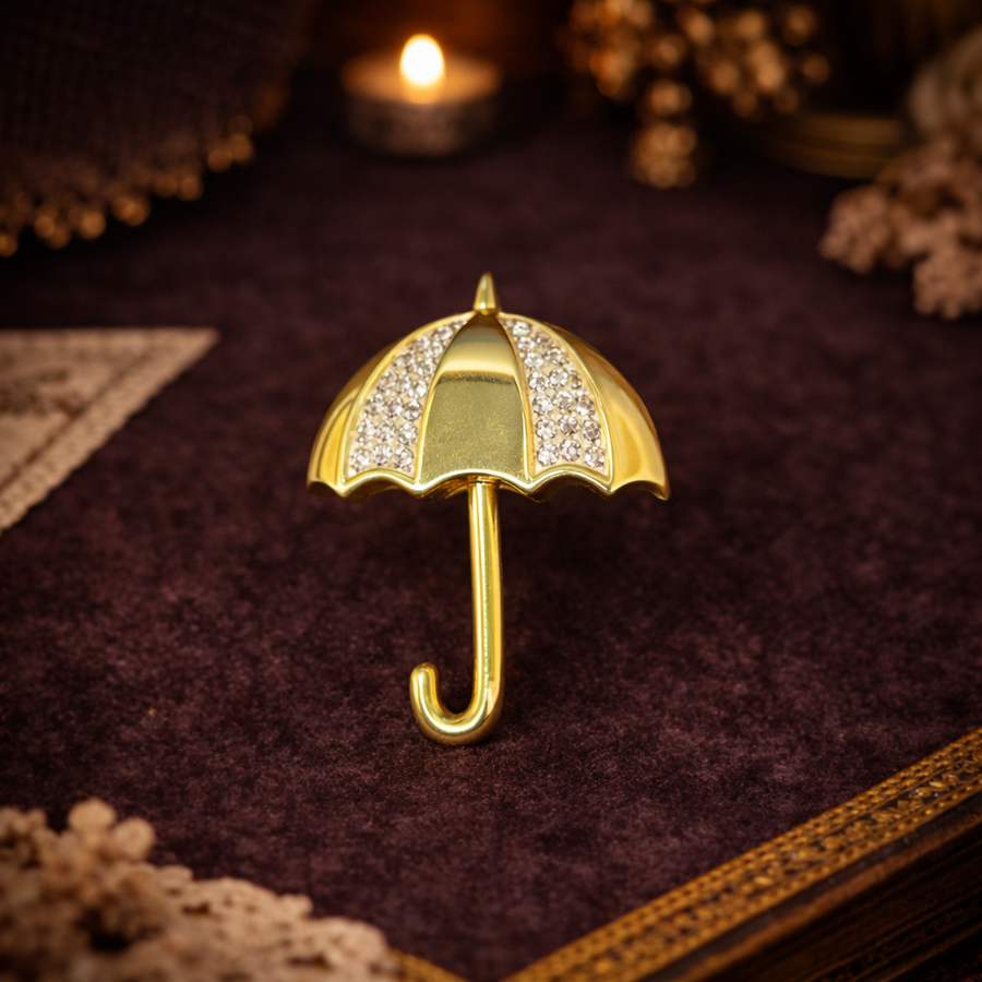 Gold-tone umbrella brooch with clear rhinestone canopy and curved handle