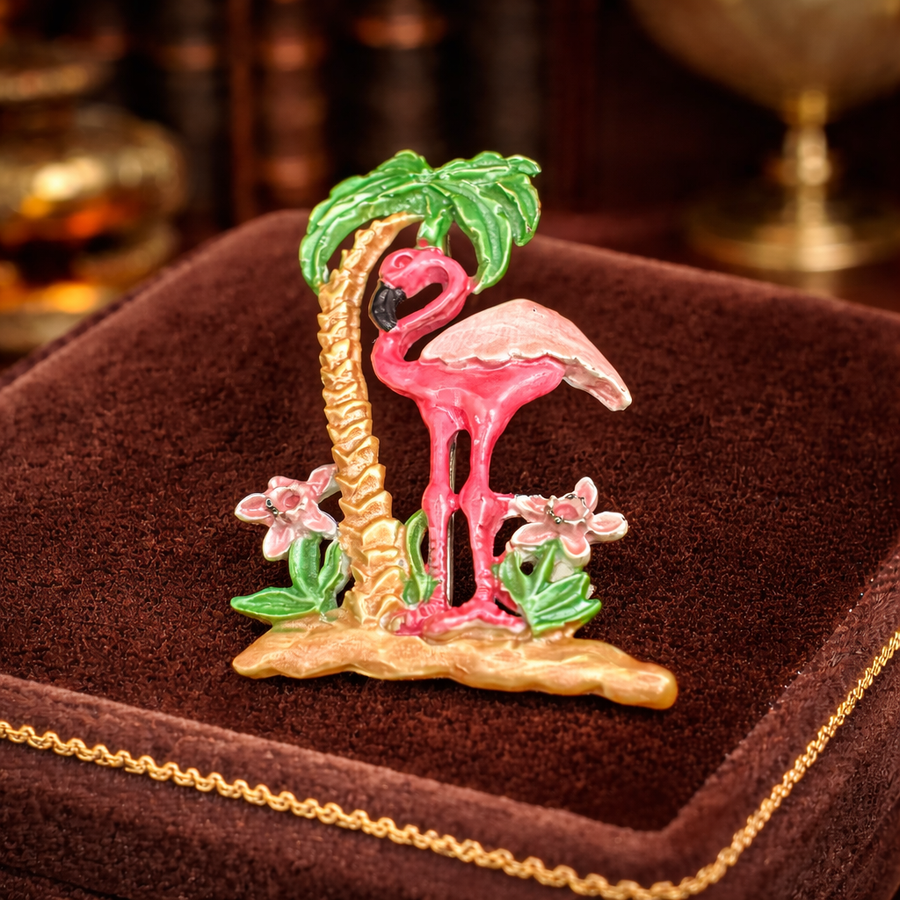 Gold-tone pink enamel flamingo brooch under a green palm tree with floral accents