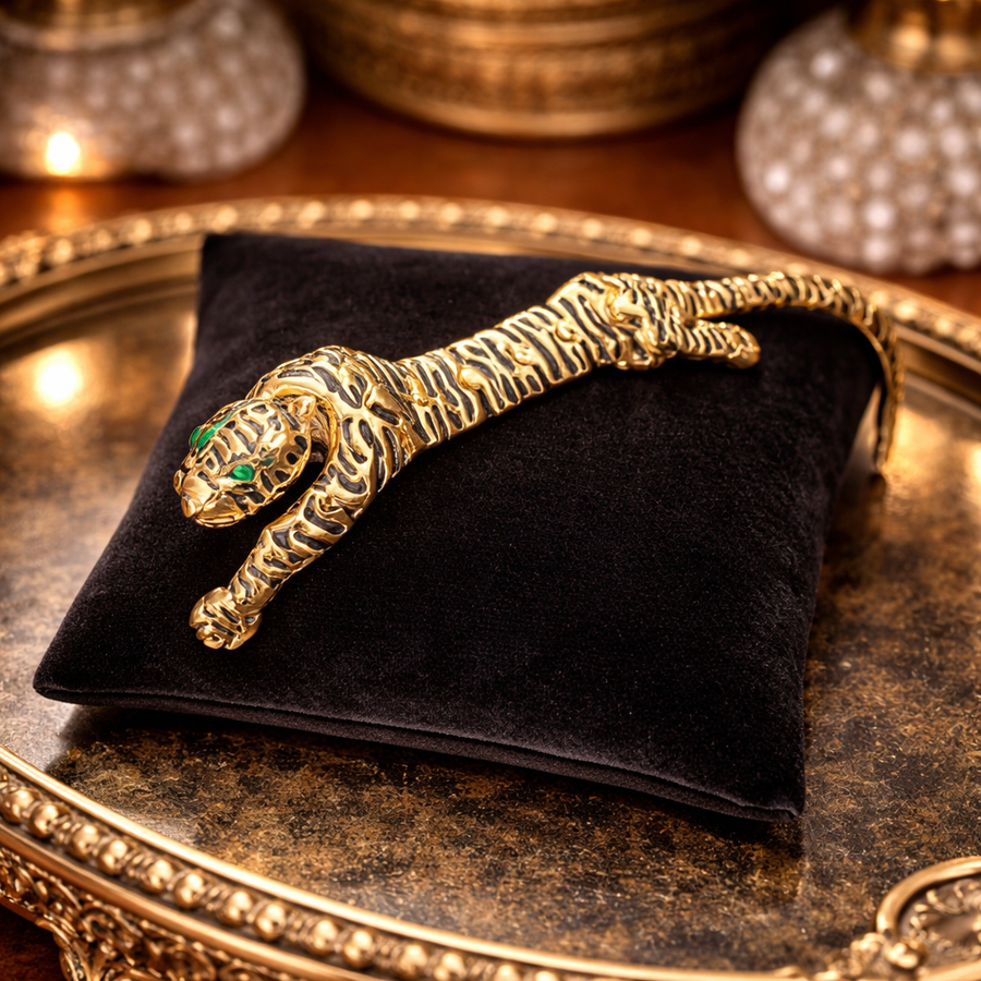 Gold-tone articulated tiger brooch with dark stripes and green eyes
