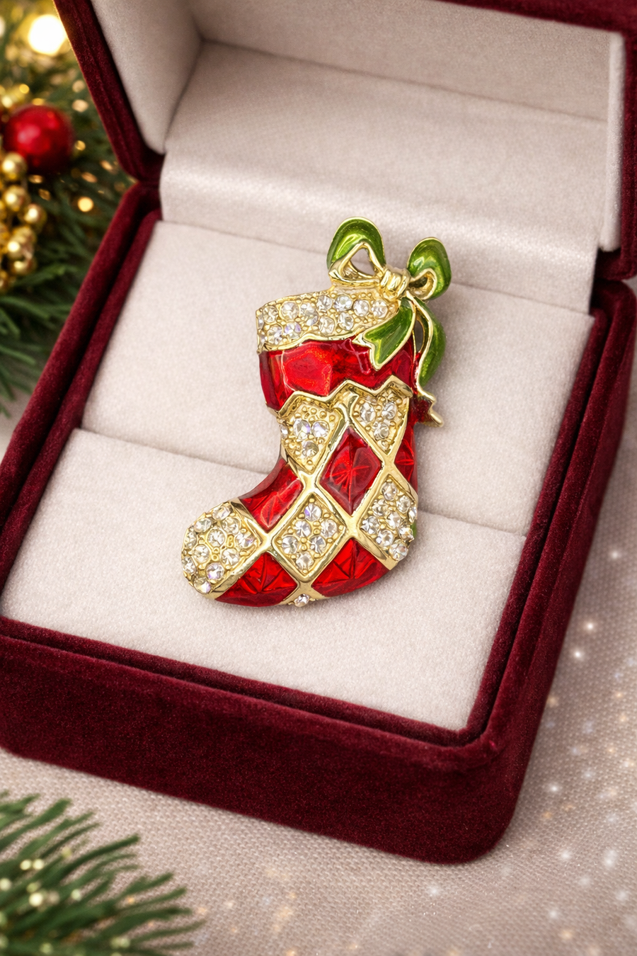 Gold-tone Christmas stocking brooch with red enamel panels, clear rhinestones and green enamel bow