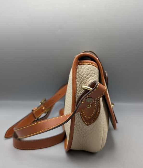 Dooney and Bourke cream pebbled leather saddle crossbody with tan trim and brass-tone duck closure, view 9