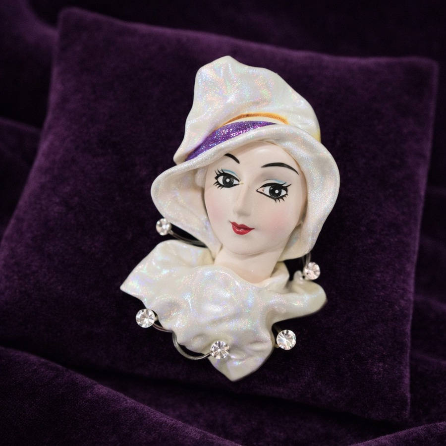 Sculpted portrait brooch of a lady with an iridescent hat and pearl-style accents