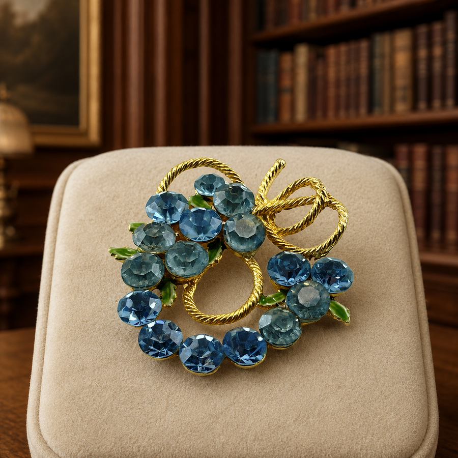 Gold-tone openwork brooch with blue rhinestone cluster and green enamel leaves