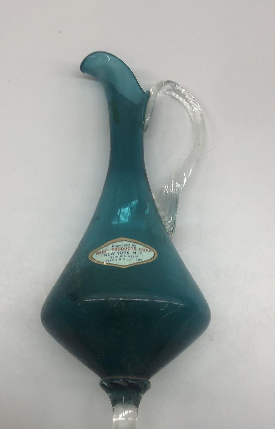 Teal glass ewer with teardrop body, curled lip, clear twisted applied handle and clear foot, view 3
