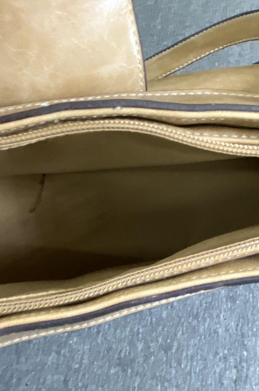 Beige shoulder bag with front buckle and side compartments holding mini pouches, view 5