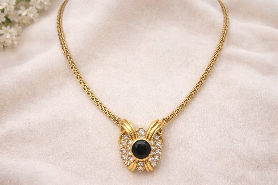 Gold-tone pendant necklace with black cabochon center framed by clear rhinestones