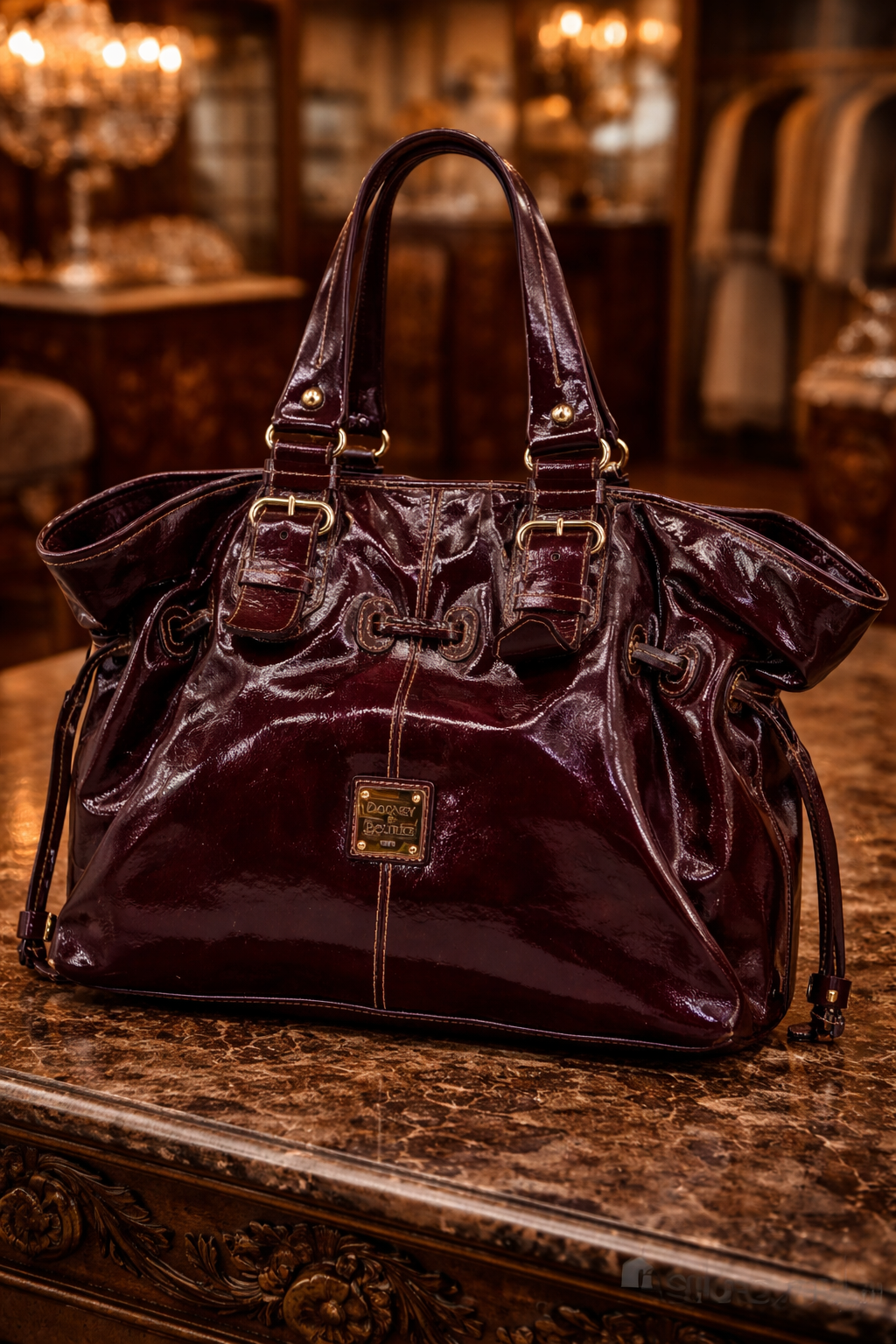 Dooney and Bourke burgundy patent leather tote with drawstring sides and buckle straps