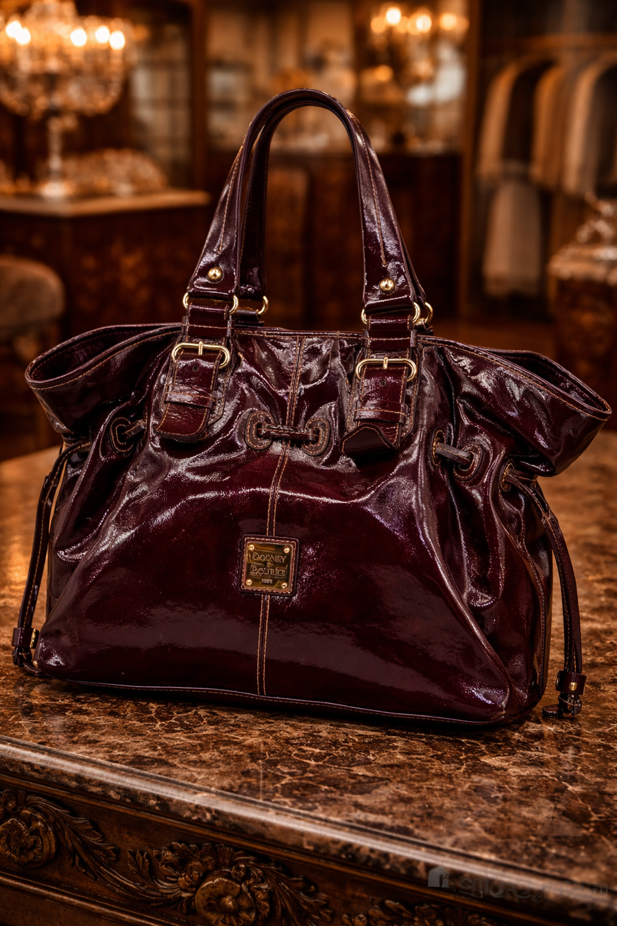 Dooney and Bourke burgundy patent leather tote with drawstring sides and buckle straps