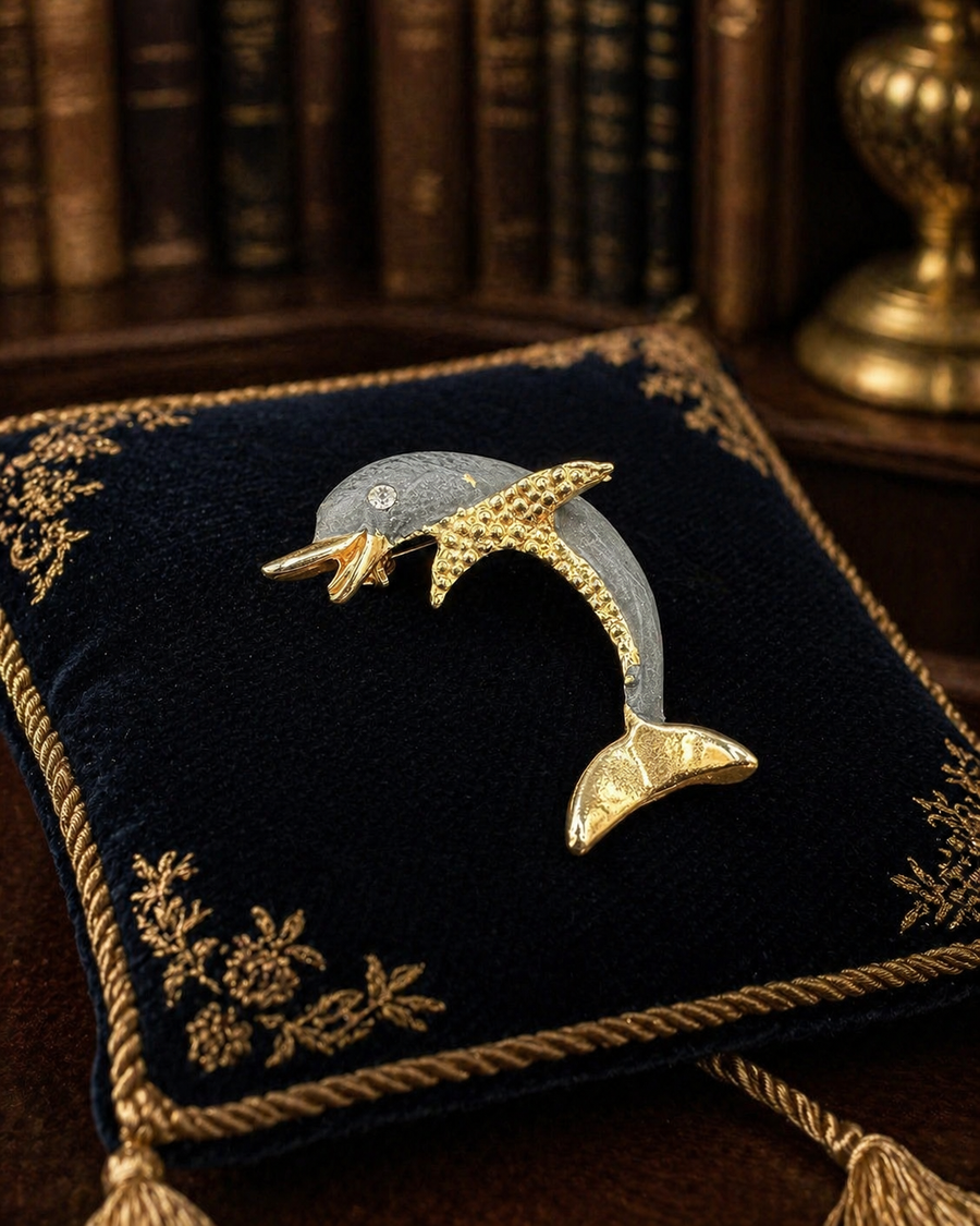 Gold-tone leaping dolphin brooch with gray body and clear crystal accents
