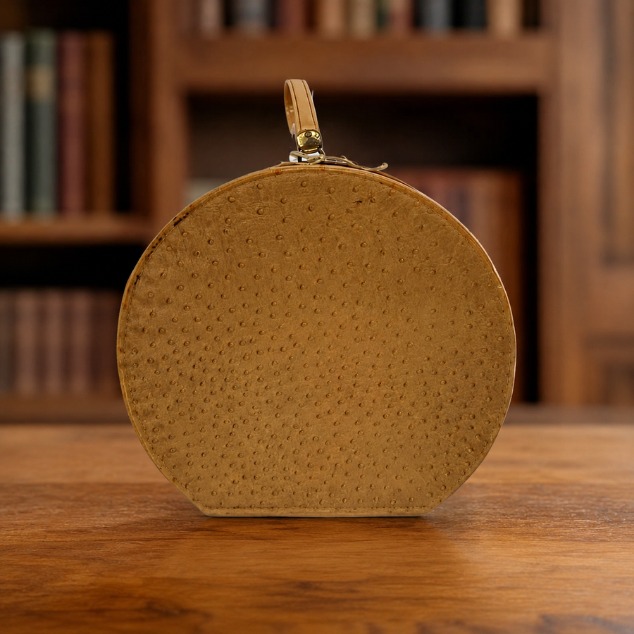 Tan ostrich-textured hard-sided round travel case with short top handle