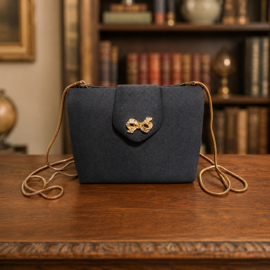Black structured evening clutch with gold-tone bow clasp and slim chain strap