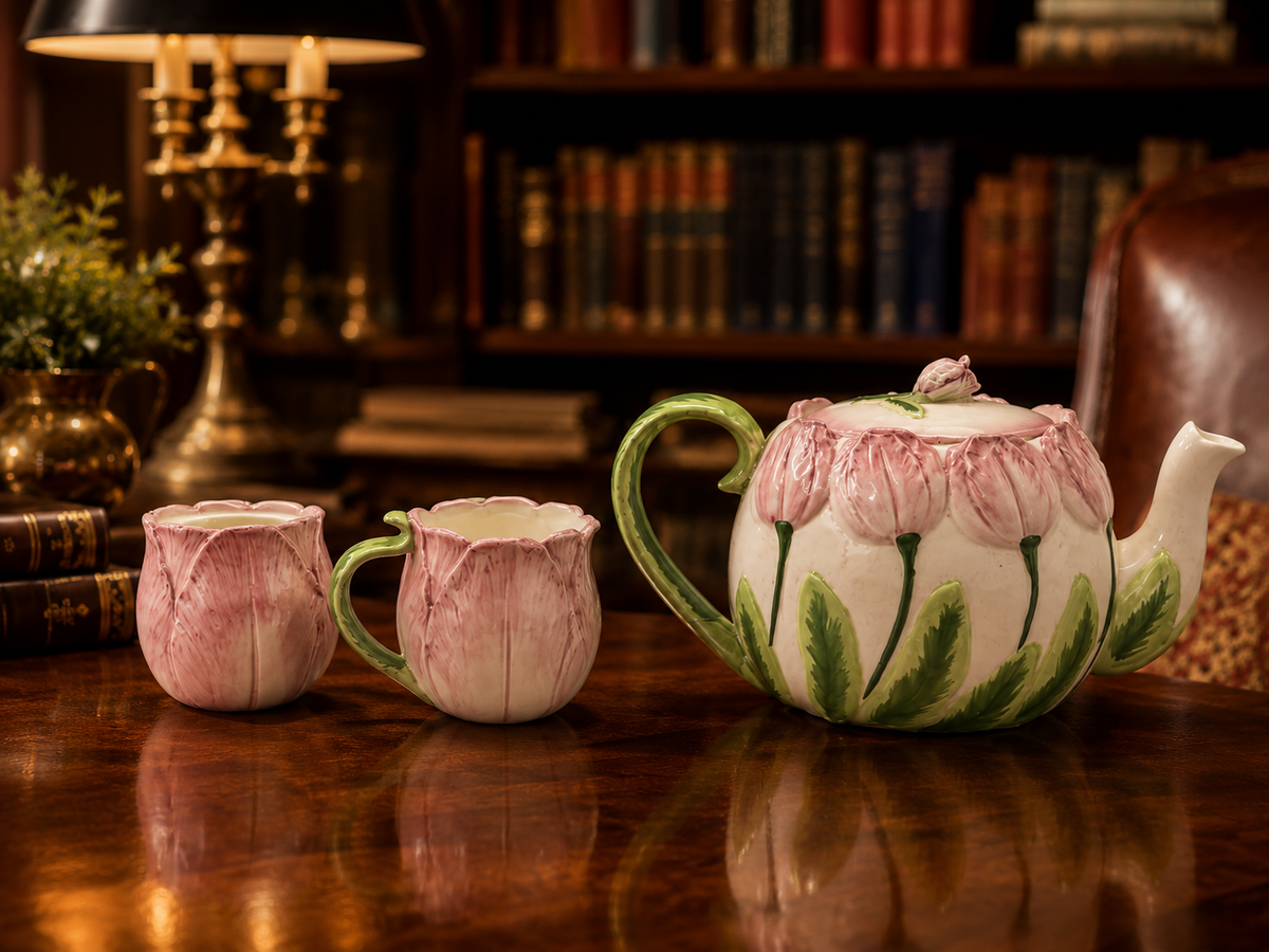Pink tulip-shaped ceramic teapot with creamer and sugar bowl and green leaf accents