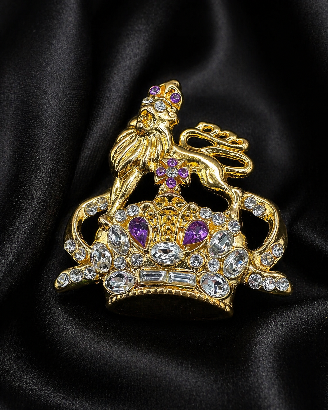 Gold-tone ornate crown brooch topped with a lion, set with clear and purple crystals