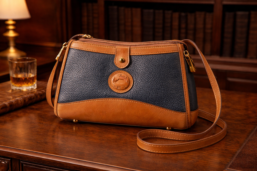 Dooney and Bourke navy pebbled leather barrel crossbody with British tan trim and duck medallion