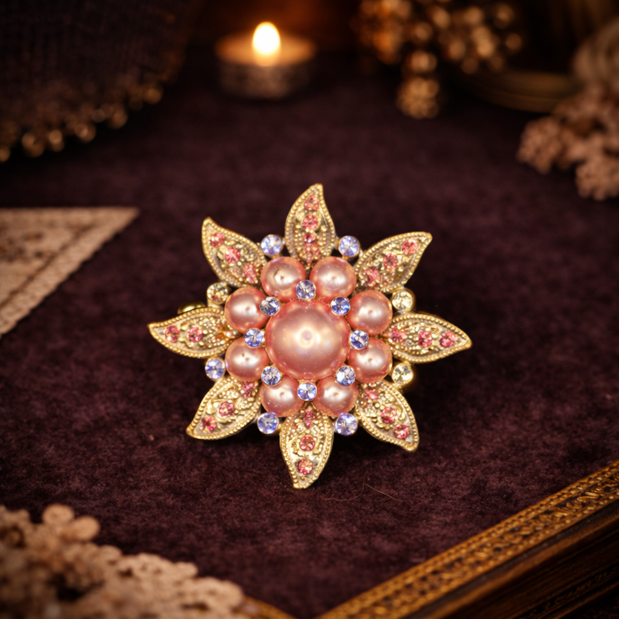 Gold-tone starburst flower brooch with pink faux pearl center and rhinestones