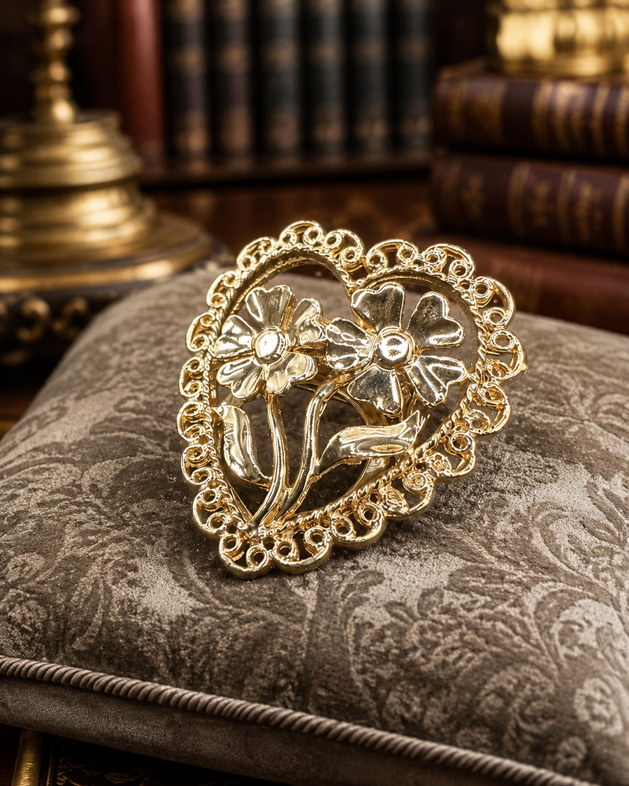 Gold-tone heart brooch with openwork border and raised flower design