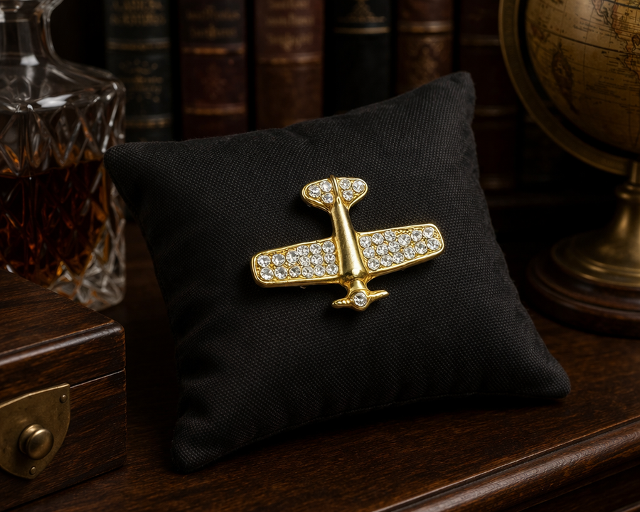 Gold-tone stylized airplane brooch with clear rhinestone accents on the wings