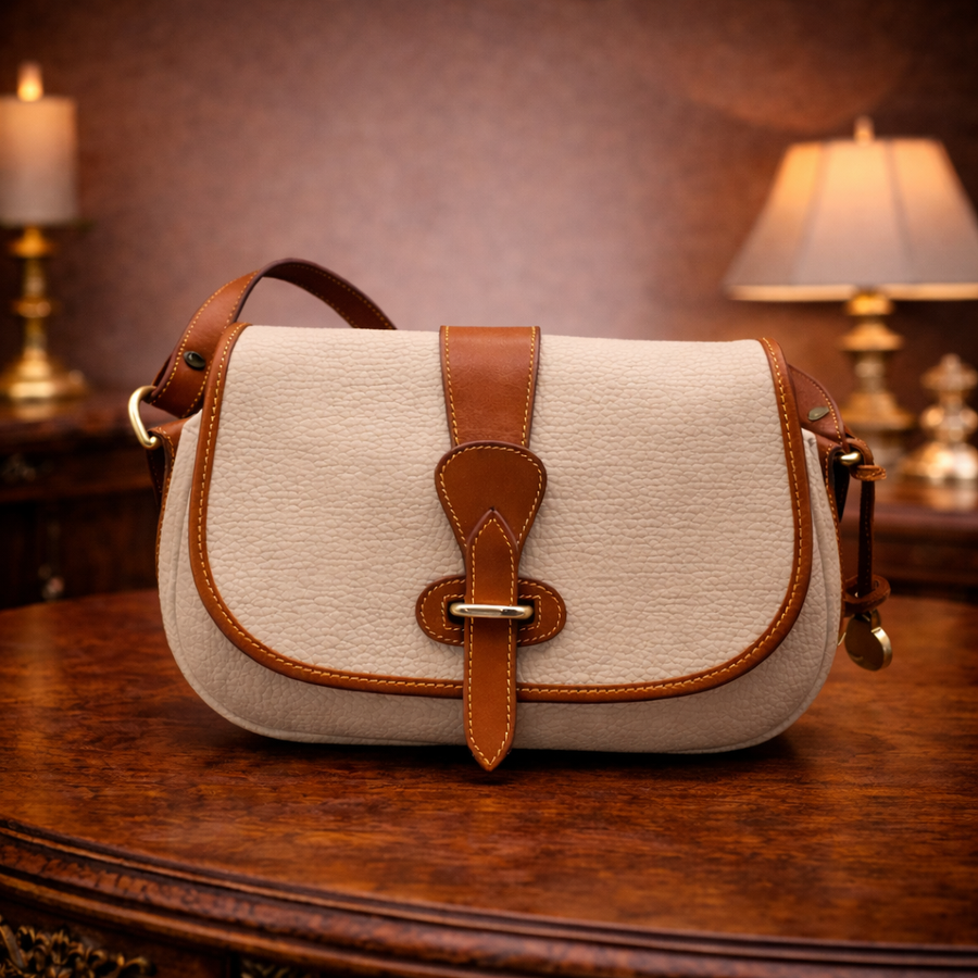 Dooney and Bourke cream pebbled leather saddle crossbody with tan trim and brass-tone duck closure