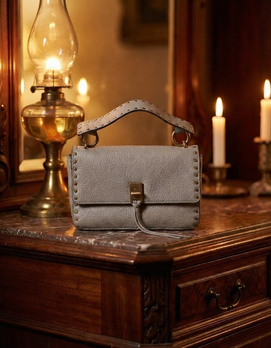 Taupe pebbled leather flap crossbody bag with studded strap, turn-lock and tassel