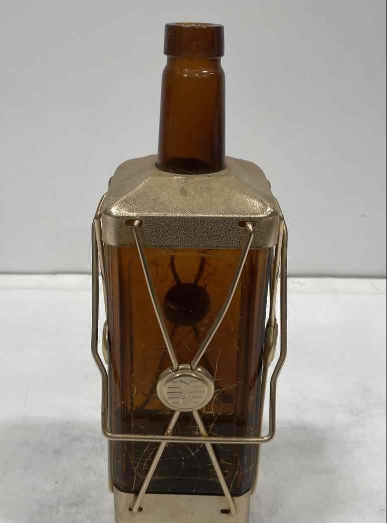 Amber glass decanter labeled Swiss Harmony Musical in a brass-tone wire caddy with medallion, view 4