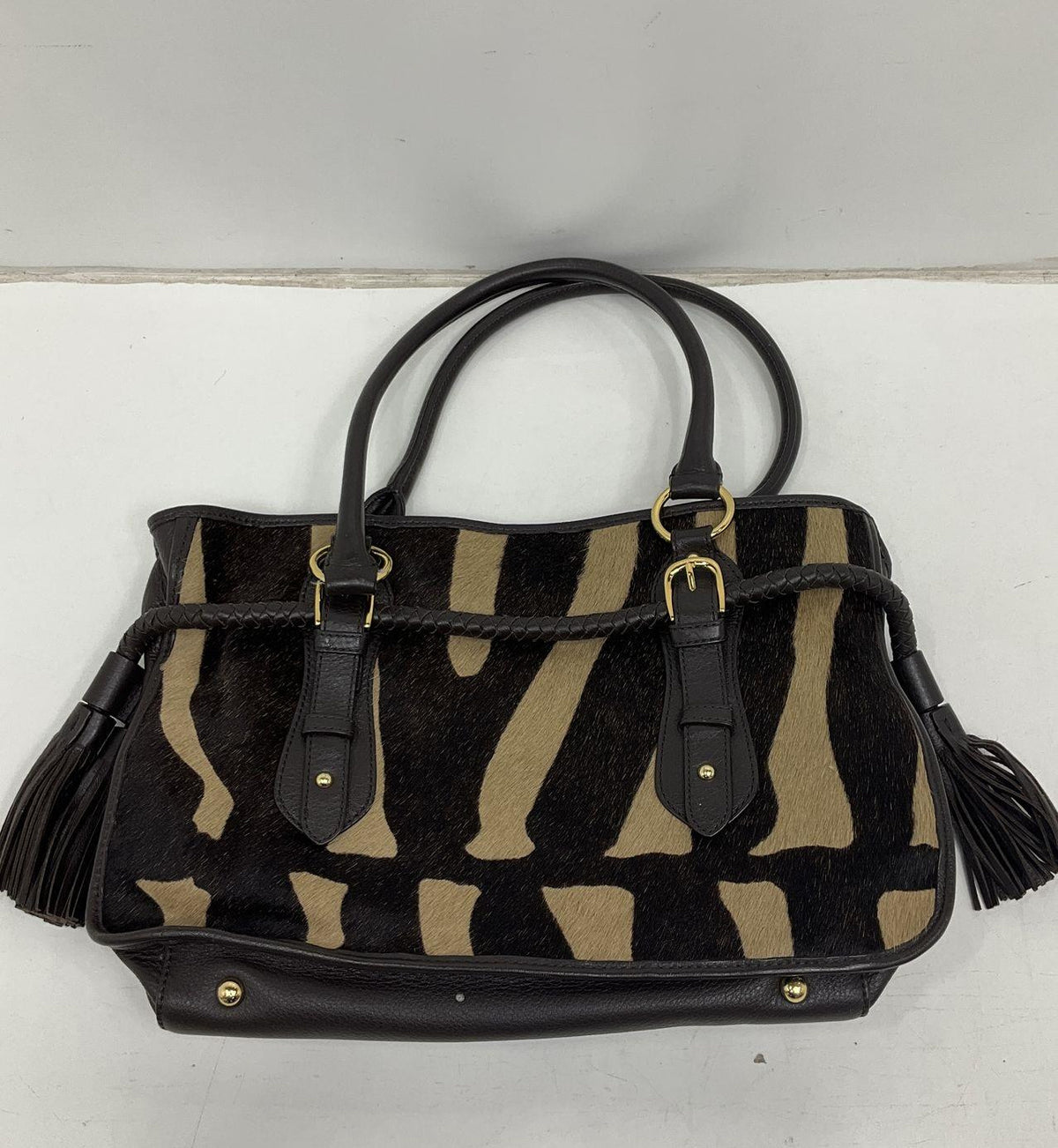 Adrienne Vittadini zebra pattern satchel with dark brown body, braided trim and side tassels, view 2