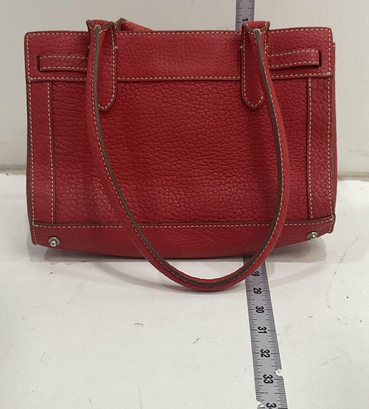 Dooney & Bourke red pebbled leather satchel with front tassel, double handles and metal feet, view 3