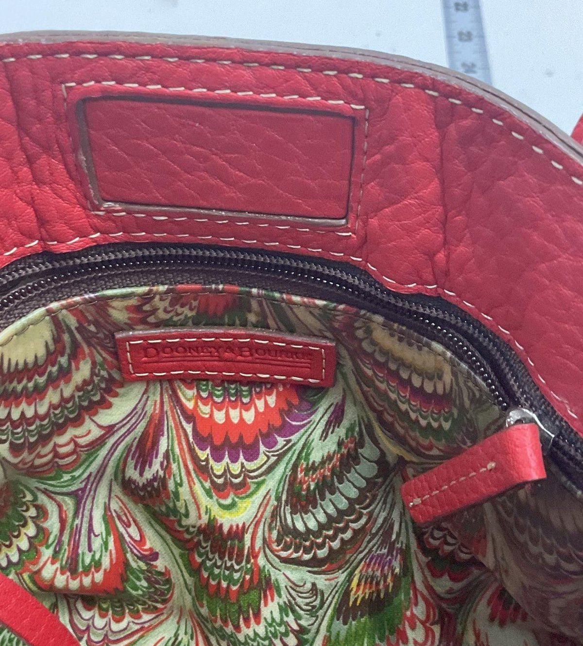 Dooney & Bourke red pebbled leather satchel with front tassel, double handles and metal feet, view 4