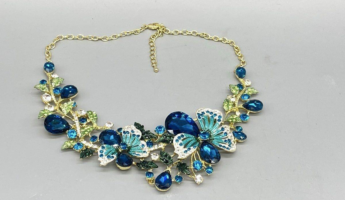 Gold-tone bib necklace of blue rhinestone flowers, leaves and turquoise enamel butterflies, view 3