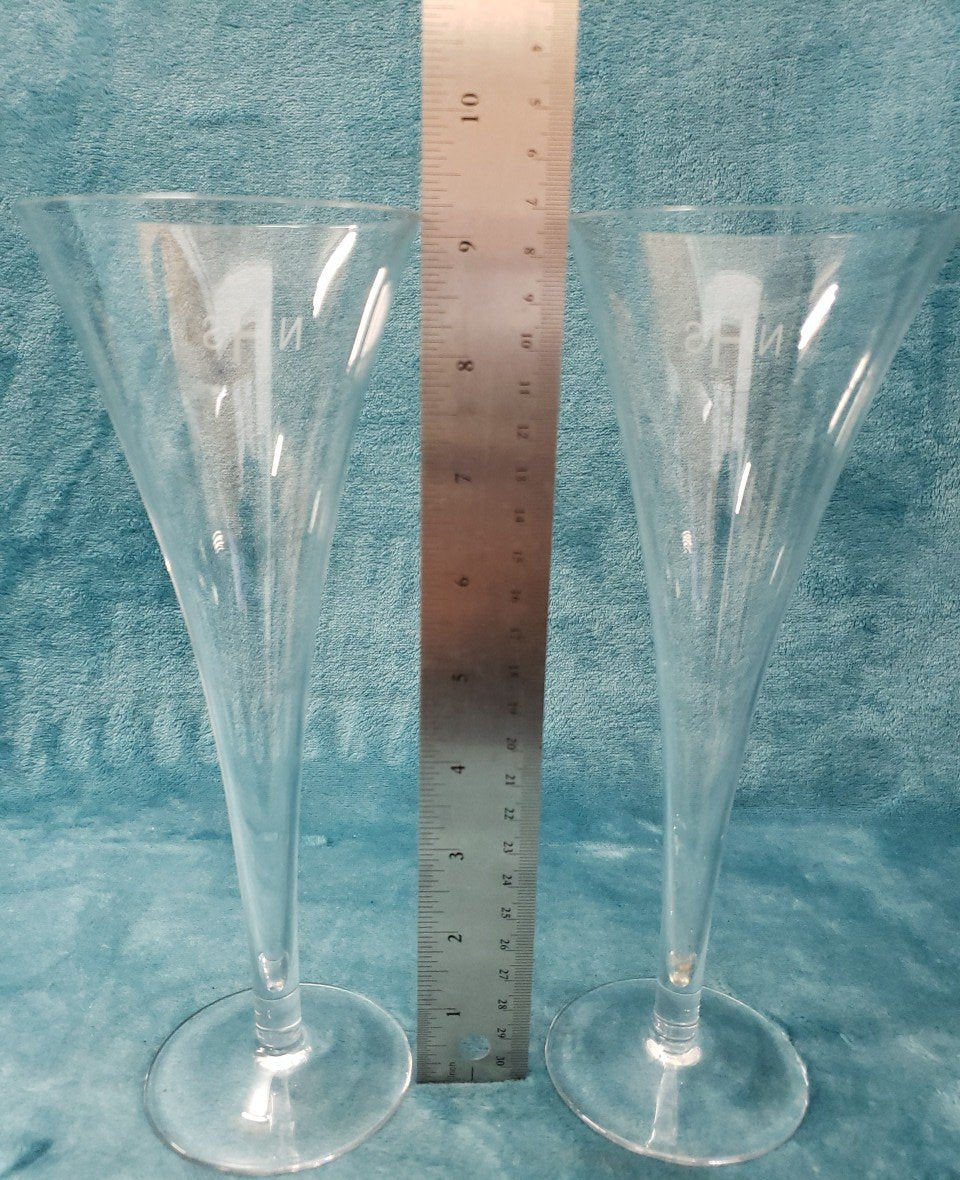 Two tall clear champagne flutes etched with the initials NHS beside a blue box, view 9