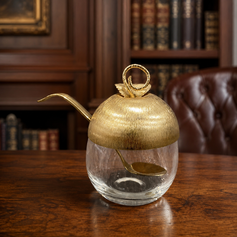 Clear glass apple-shaped sugar bowl with gold-tone leaf lid and long spoon
