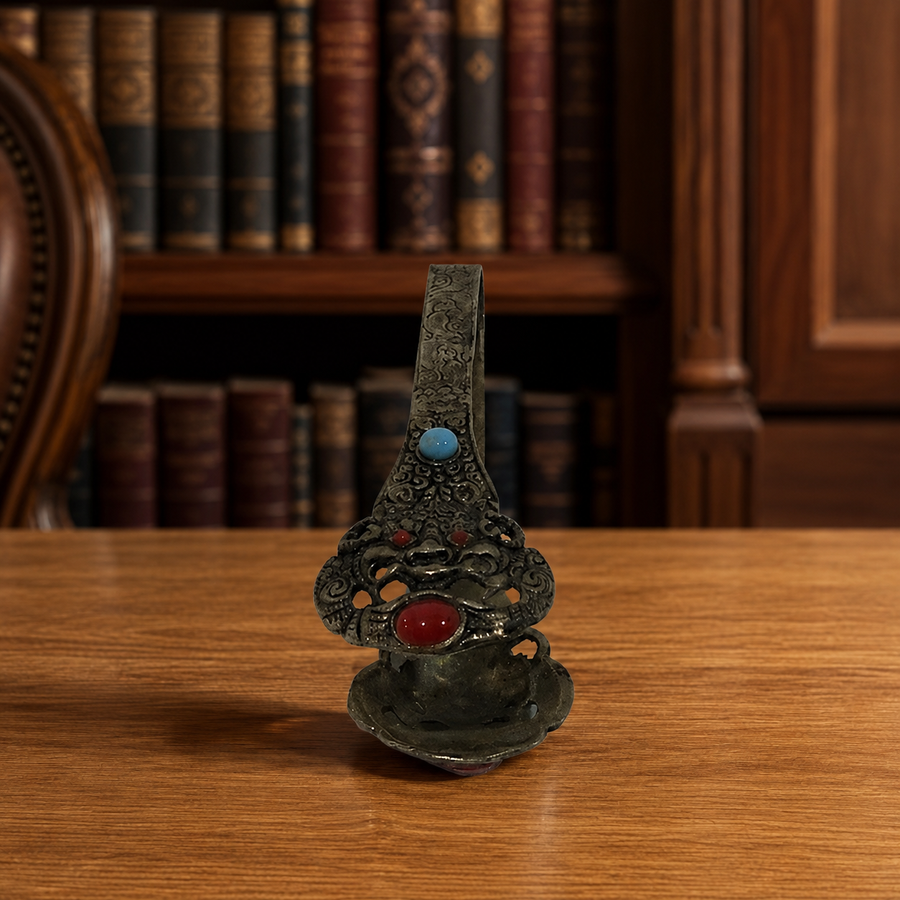 Ornate metal tongs with filigree-style detail and red and turquoise-tone cabochon-style accents