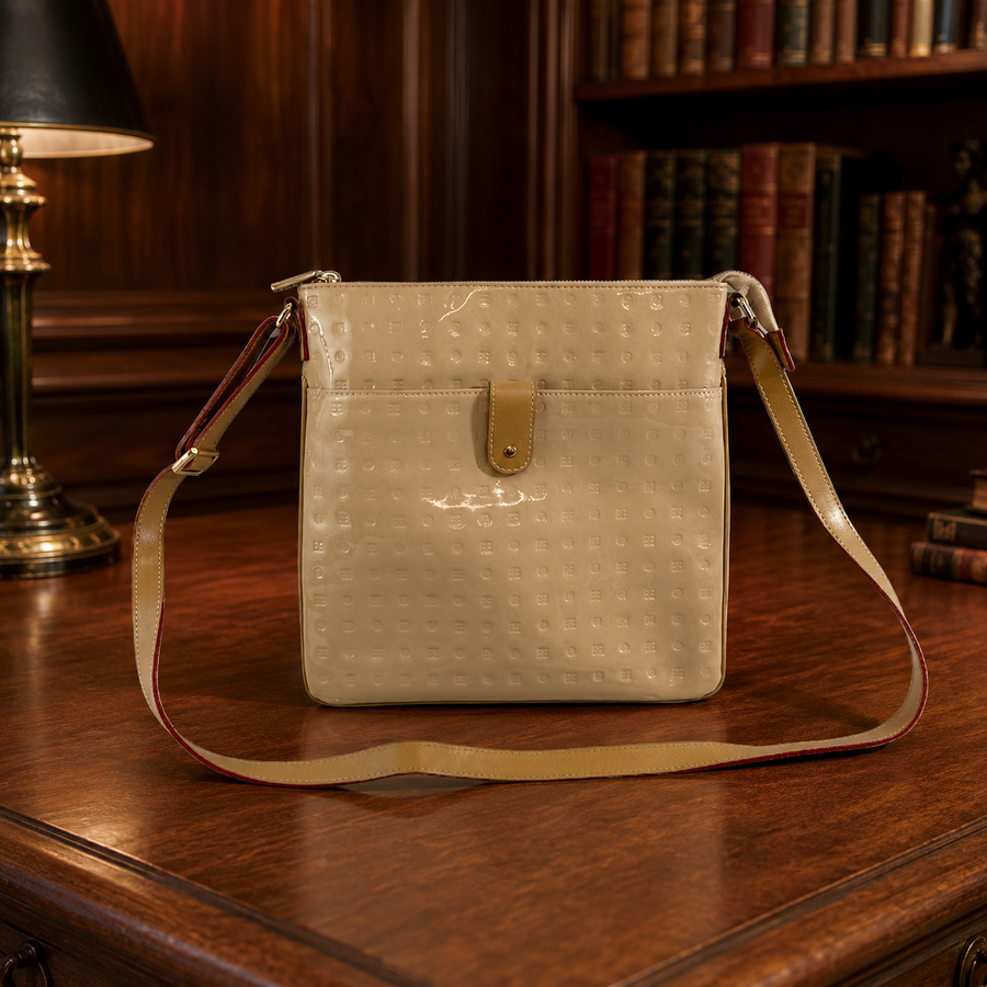 Arcadia cream patent leather sling bag with flap front and gold-tone brand plate