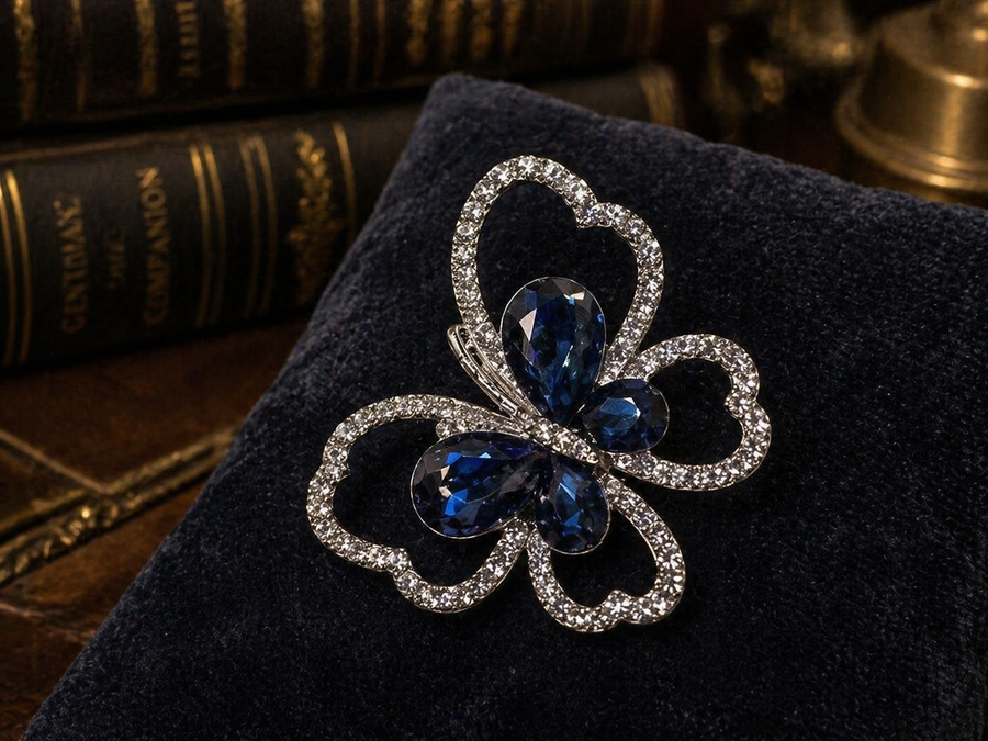 Silver-tone openwork butterfly brooch with deep blue crystal wings on display card