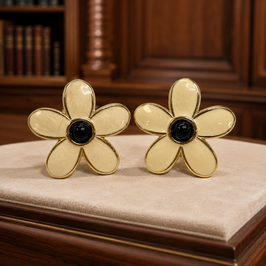 Signed Monet gold-tone clip-on earrings with cream enamel petals and black stone centers