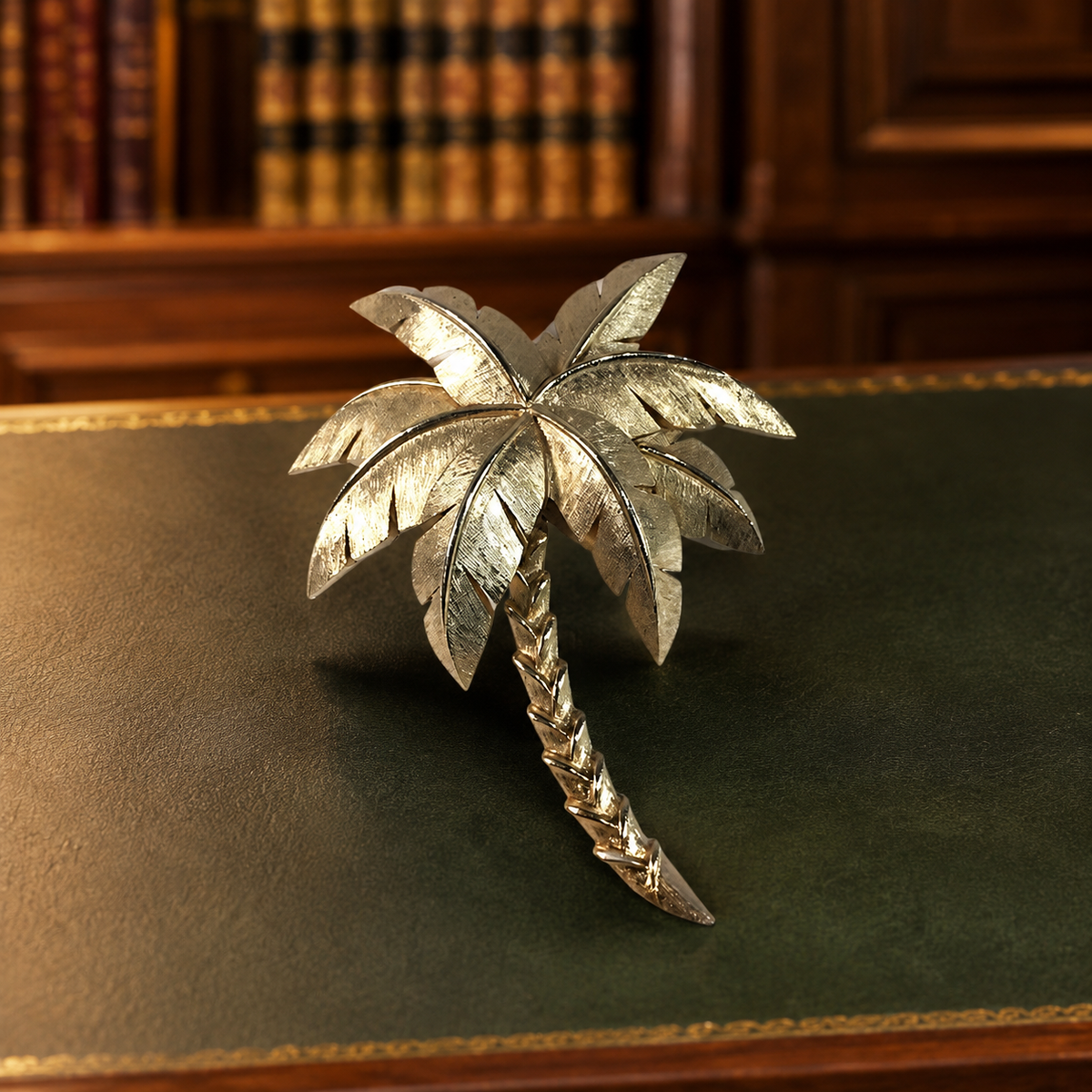 Gold-tone palm tree brooch with textured fronds and curved trunk