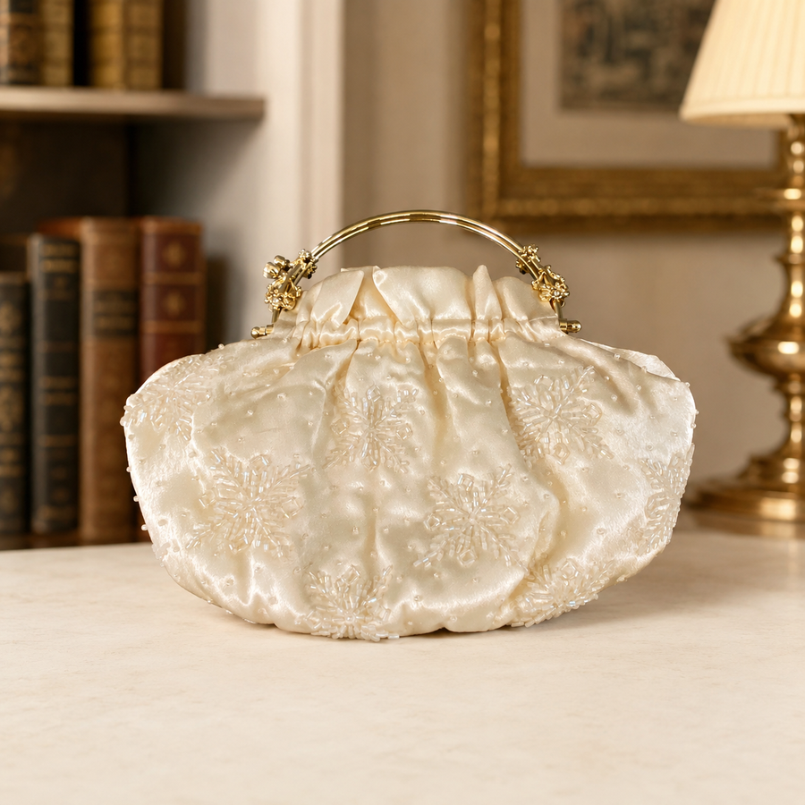 Off-white cream gathered clutch with gold-tone top handle frame and floral rhinestone accents